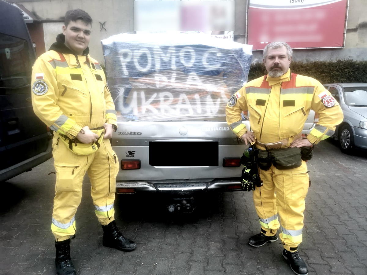 dwóch mężczyzn przed samochodem z flagą Ukrainy i napisem pomoc dla Ukrainy, po lewej Daniel Skabek rudzki policjant, po prawej dowódca Grupy Poszukiwawczo-Ratunkowej 13 Orzesze, zdjęcie FB 13orzesze