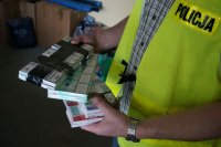 Policjant operacyjny prezentuje przejęte papierosy bez polskich znaków akcyzy