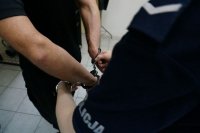 Policjant zakłada kajdanki zatrzymanemu