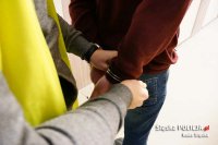 Policjant zakłada kajdanki zatrzymanemu