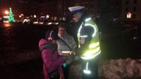 Policjant przekazuje odblaskową opaskę