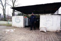 Dzielnicowy st.asp. Piotr Nowak przed śmietnikową wiatą