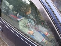 Dziecko w samochodzie na przednim siedzeniu zapięte w pasy