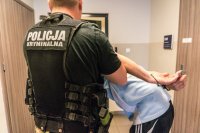 Policjant konwojuje zatrzymanego