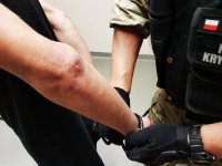 Policjant zakłada kajdanki jednemu z zatrzymanych braci
