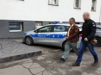 Policjant prowadzi włamywacza na przesłuchanie