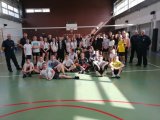 Zdjęcie zbiorowe uczestników turnieju - hala sportowa dzieci stojące i siedzące po obu bokach policjanci w mundurach.