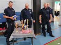 Zdjęcie - czterech policjantów w mundurach, przed nimi stolik z medalami i pucharami