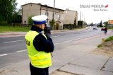 Zdjęcie - umundurowany policjant drogówki z radarowym miernikiem prędkości - tło ulica i zabudowania