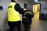 zdjęcie poglądowe - policjant prowadzi zatrzymanego (na rękach kajdanki)