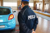 Policjant z drogówki, w tle samochód na stanowisku stacji diagnostycznej