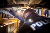 Zdjęcie - kanał stanowiska diagnostycznego - policjant na pierwszym planie i za nim diagnosta sprawdzający elementy podwozia samochodu