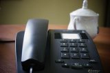 zdjęcie poglądowe - telefon stacjonarny na stole, a w tle cukiernica