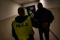 zdjęcie - policjanci prowadzą zatrzymanych korytarzem
