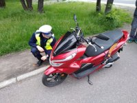 zdjęcie przedstawia policjanta drogówki kontrolującego stan techniczny motocykla