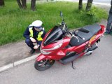 zdjęcie przedstawia policjanta drogówki kontrolującego stan techniczny motocykla