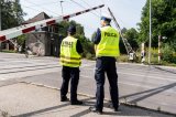 Zdjęcie przedstawia policjanta drogówki i funkcjonariusza SOK przy przejeździe kolejowym