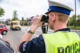 zdjęcie przedstawia policjanta drogówki z lornetką, w tle samochód dostawczy. Zdjęcie poglądowe