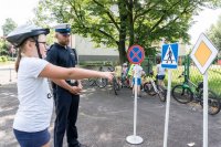 zdjęcie przedstawia - policjanta i dziewczynkę wskazującą ręką znak dorgowy