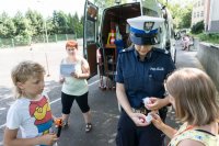 zdjęcie przedstawia - policjantkę wręczającą lampki rowerowe uczestniczce egzaminu