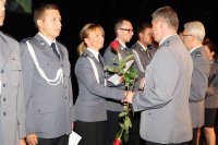 Zdjęcie z uroczystości Święta Policji przedstawia wręczanie aktów nominacyjnych ustawionym w rzędzie funkcjonariuszom