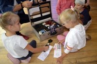 zdjęcie przedstawia dzieci w trakcie zajęć z poszukiwania śladów - oglądają walizkę technika