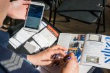 zdjęcie przedstawia dzielnicowego wypełniającego formularze kontaktowe dla obywateli i telefon z uruchomioną aplikacją moja komenda