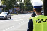 zdjęcie przedstawia policjanta drogówki a w tle skrzyżowanie z sygnalizacją świetlną