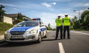 zdjęcie ukazujące stojący na drodze radiowóz i dwoje policjantów z drogówki obok