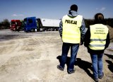 teren poprzemysłowy - w tle dwa samochody ciężarowe a na pierwszym planie policjant i pracownica inspekcji ochrony środowiska