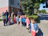 Policjanci z przedszkolakami na chodniku w rejonie przejścia dla pieszych