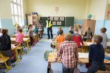 klasa, dzieci przy ławkach szkolnych słuchają policjanta stojącego przy tablicy