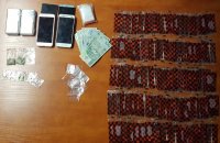 na biurku rozłożone woreczki z dopalaczami i narkotykami, telefony, wagi i pieniądze