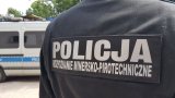 zdjęcie przedstawia policyjnego pirotechnika tyłem a w tle radiowóz policyjhny
