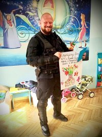 zdjęcie kolorowe - policjant trzyma w rękach plakat z podziękowaniami od przedszkolaków