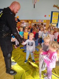 zdjęcie kolorowe - policjant w ubraniu ochronnym w trakcie wizyty w przedszkolu