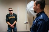zdjęcie - policjant i kierowca w pomieszczeniu do wykonywania zdjęć sygnalitycznych
