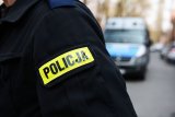 zdjęcie - ręka policjanta w mundurze i w tle radiowóz