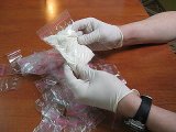 zdjęcie poglądowe - ręce w rękawiczkach gumowych trzymające woreczek z białym proszkiem