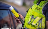 policjant z alkotestem przy samochodzie