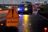 droga, policyjny radiowóz z włączonymi światłami niebieskimi, na pierwszym planie znak uwaga wypadek