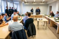 sala szkoleniowa, siedzący uczestnicy ćwiczeń a w oddali komendant i policjanci