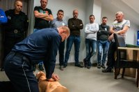policjant pokazuje rezerwistom jak wykonywać masaż serca na fantomie
