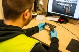 policyjny technik trzymający znaleziony pistolet