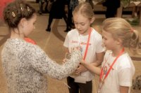 zdjęcie przedstawia trzy dziewczynki, dwie wolontariuszki z puszką i jedna składająca datek