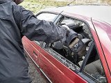 samochód z wybitą szybą w drzwiach i osoba wyciągająca torbę ze środka. zdjęcie poglądowe