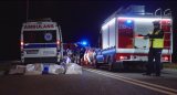 karetka, straż pożarna, cztery worki na zwłoki na jezdni i policjant drogówki kierujący ruchem