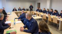 odprawa roczna - sala odpraw przy stołach siedzący policjanci, pracownicy cywilni i zaproszeni goście