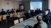 odprawa roczna - sala odpraw przy stołach siedzący policjanci, pracownicy cywilni i zaproszeni goście