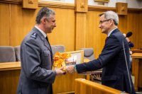 zdjęcie kolorowe przedstawia uroczystość pożegnania odchodzącego komendanta - sala sesyjna zastępca prezydenta wręcza upominek komendantowi